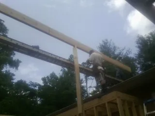 Carpenter setting a ridge beam over a new addition frame — Ice Dam Removal by Roofing Brothers in Clontarf