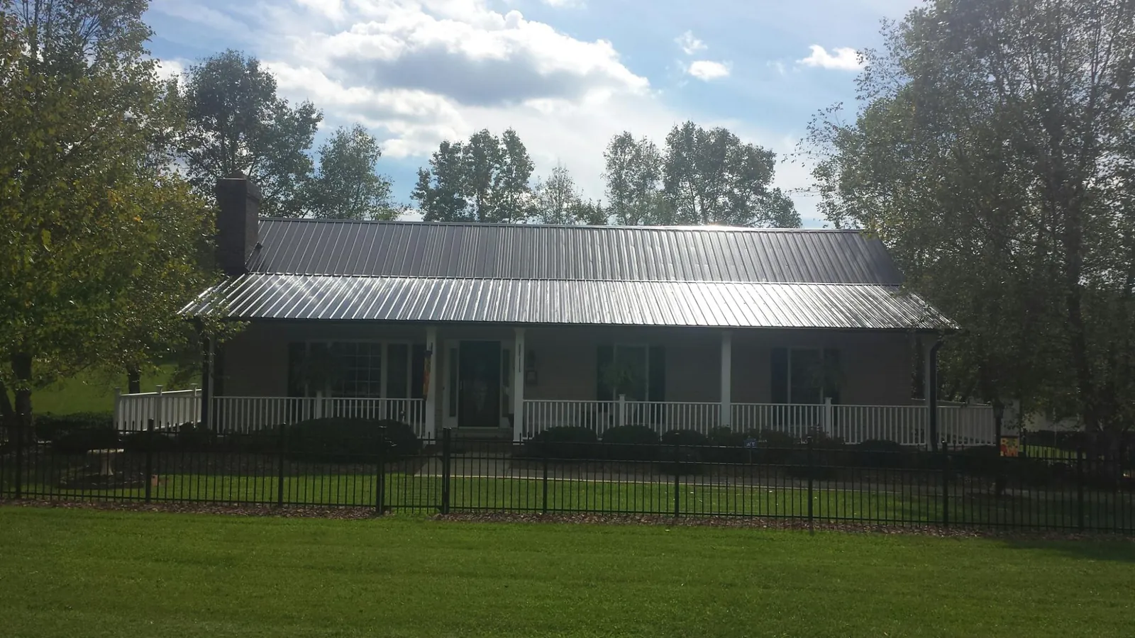 Gray metal roof on a brick ranch with a full width front porch — Gutter Guard Installation work by our crew in Clontarf