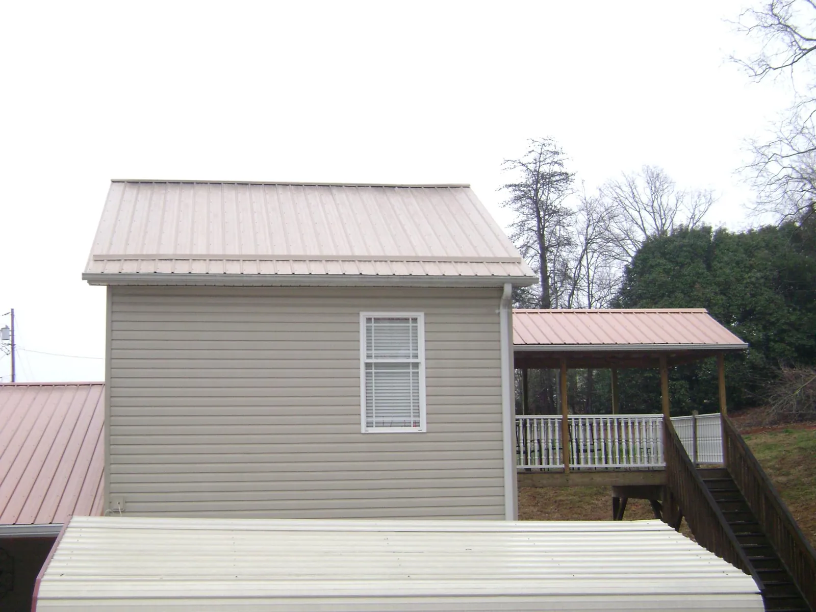 Tan metal roofs on a two story addition and attached porch, from a Roof Replacement job in Clontarf