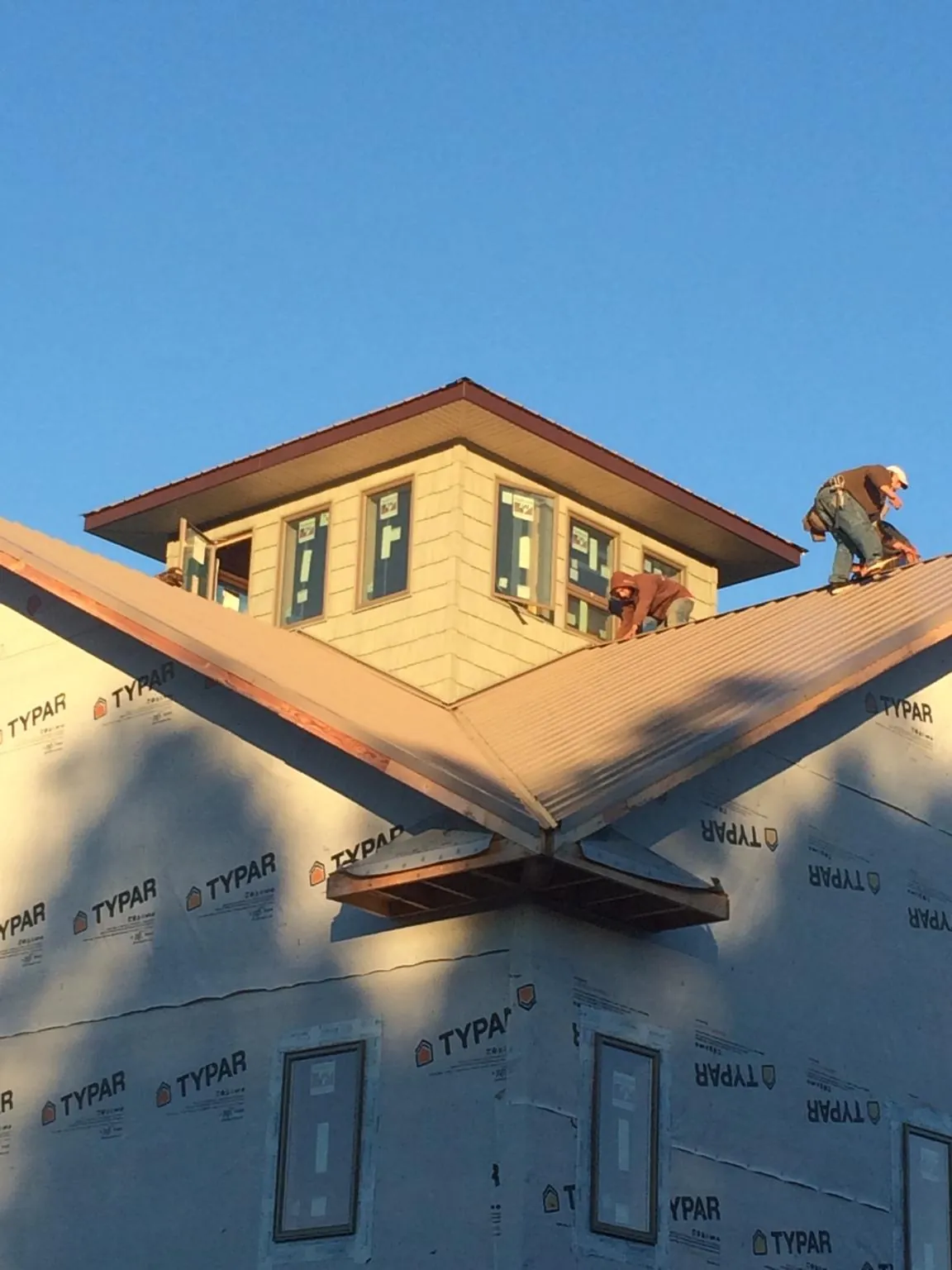 Roofers working around a rooftop cupola on a new metal roof at sunset — Roof Waterproofing in Clontarf by Roofing Brothers